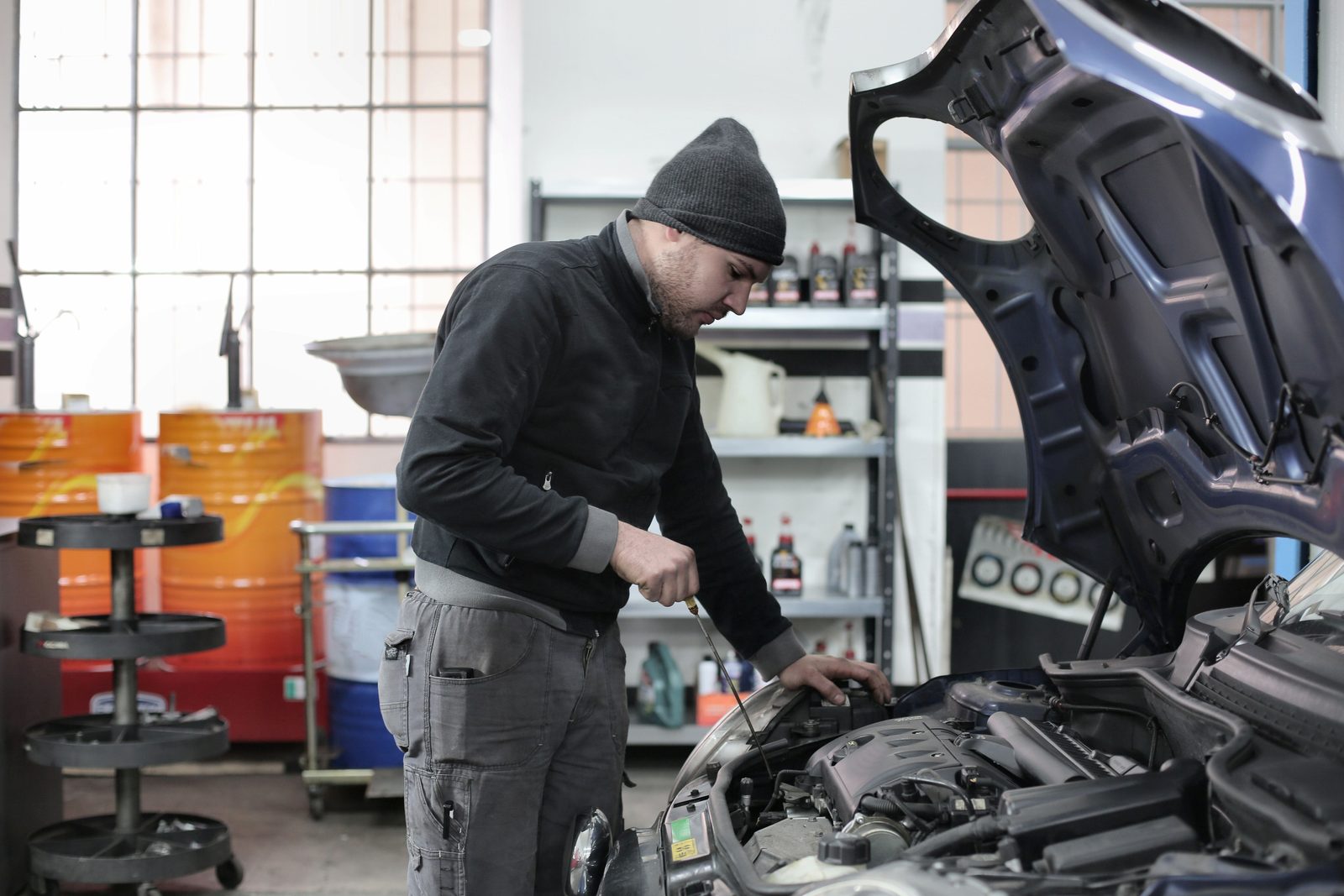 Mechanic inspecting a car engine in a garage workshop.